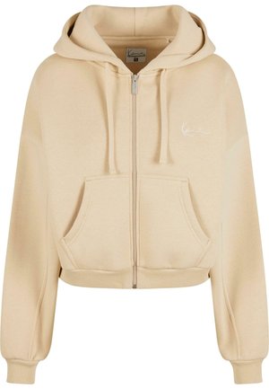 Béžová skrátená mikina na zips so sťahovacou kapucňou, prednými vreckami a mäkkou textúrou. Obsahuje jemne vyšívané logo na hrudi.