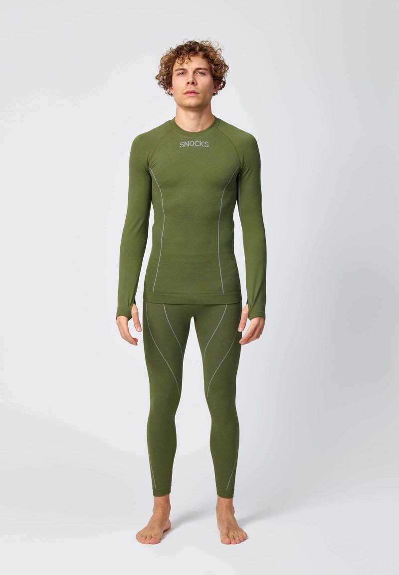 Langsleeve, getailleerde groene thermoshirt en bijpassende leggings met grijze stikseldetails. Ontworpen voor comfort en warmte. Zachte textuur.