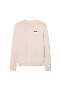 Suéter beige de cuello redondo hecho de un tejido suave. Presenta puños y dobladillo acanalados, con un pequeño parche de logo negro en el pecho. Ajuste clásico.