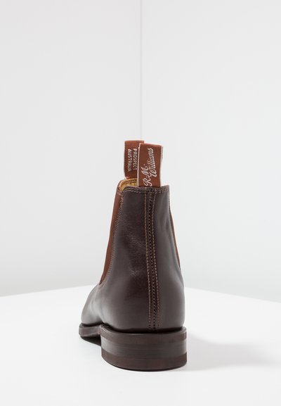 Brown leather ankle boot with a smooth finish, elastic side panels, and a sturdy brown sole. Features brand label on back loop.