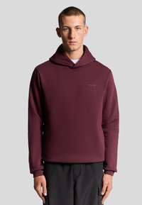 Bordeaux hættebluse med en blød tekstur, der har en frontlomme og diskret branding. Lange ærmer og en løs pasform supplerer designet.