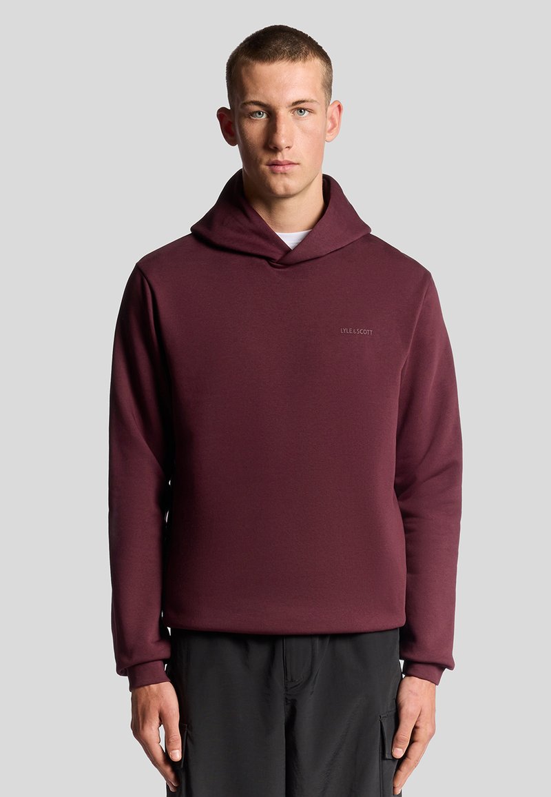 Bordeaux hættebluse med en blød tekstur, der har en frontlomme og diskret branding. Lange ærmer og en løs pasform supplerer designet.
