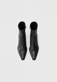 Botas de cuero negras hasta el tobillo con punta afilada, cierre de cremallera en la parte posterior y un diseño elegante y estilizado. Textura suave.