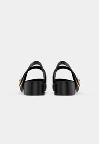 Black leather sandals with a block heel and a gold accent on the strap. Features open back and thick straps for support.