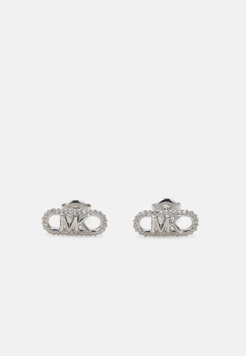 Pendientes de plata con forma ovalada y un logo MK en relieve, rodeado de un borde texturizado de pequeñas piedras.