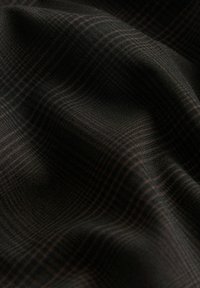 Tessuto nero con un sottile motivo a scacchi in tonalità di grigio scuro e marrone, caratterizzato da una superficie liscia e texture che si drappeggia dolcemente.