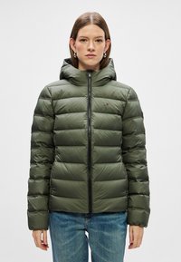 Chaqueta acolchada verde con cierre delantero, capucha y puños elásticos. Presenta un diseño acolchado y un pequeño logo en el pecho.