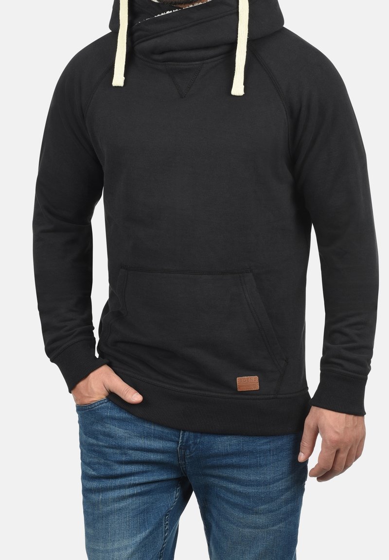 Sudadera negra hecha de tejido suave, con cuello alto, cordones y un bolsillo frontal. Incluye una etiqueta de marca de cuero en el dobladillo.