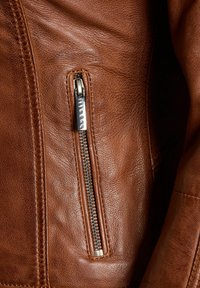 Bruine leren jas met een zichtbare zijrits en een getextureerd oppervlak. De rits is van metaal met een zilveren afwerking, wat het ontwerp versterkt.