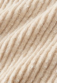 Beige ribbelstof met een zachte textuur, verticale lijnen en kleine witte spikkels doorheen, wat een warme, uitnodigende uitstraling creëert.