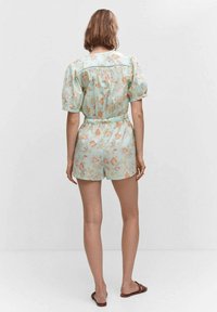 Romper w kwiatowy wzór w jasnoniebieskim kolorze, z krótkimi rękawami, zwężoną talią i guzikiem z tyłu; wykonany z miękkiego materiału.
