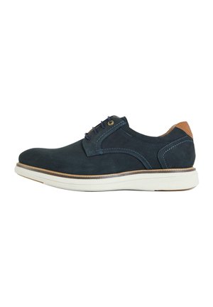Men's navy blue casual leather shoe with white sole, blue stitching, lace-up front, and tan heel accent, shown from side.