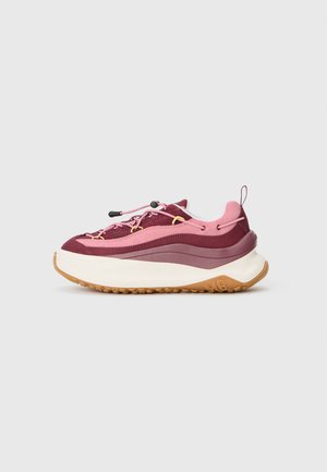 Baskets de sport marron et rose avec une tige texturée, des lacets élastiques et une épaisse semelle intermédiaire blanche avec une semelle extérieure en caoutchouc naturel.