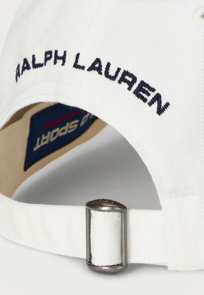 Boné de algodão branco com o texto "RALPH LAUREN" bordado. Inclui um ajustador metálico na parte de trás e uma etiqueta da marca azul no interior.
