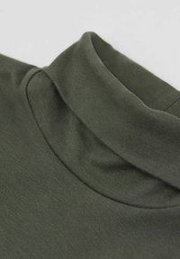 Grünes Baumwolltop mit Stehkragen und glatter Textur, das eine Nahaufnahme zeigt und den weichen Stoff sowie die Verarbeitung hervorhebt.