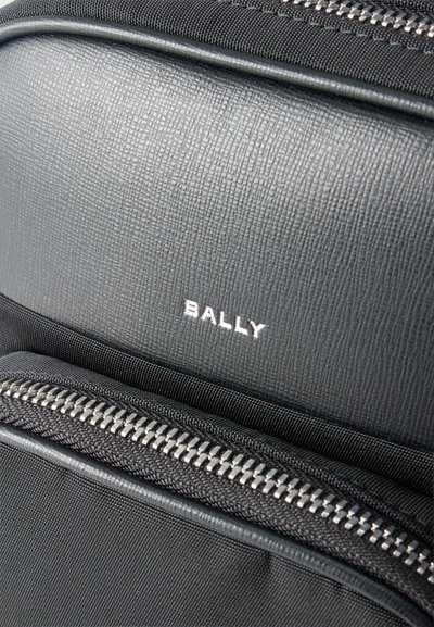 Gros plan sur un sac Bally noir avec un panneau en cuir texturé et des fermetures éclair argentées visibles.