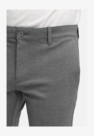 Pantaloni ajustați gri dintr-un material texturat, cu închidere prin buton la talie, buzunare laterale și o croială elegantă, modernă.