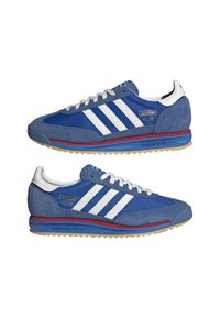 Niebieskie sneakersy Adidas SL '72 z białymi paskami, zamszowymi akcentami, czerwoną i niebieską podeszwą, pokazywane z widoku bocznego na białym tle.