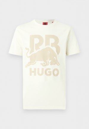 T-shirt bianca a maniche corte con grafica di un toro carica beige, grandi lettere "RB" e testo "HUGO" sul davanti.