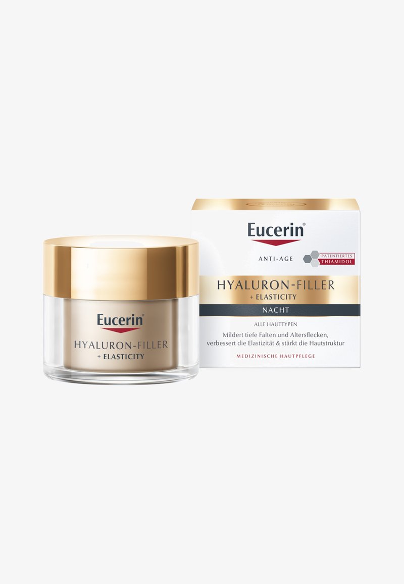 Eucerin Hyaluron-Filler + Elasticity Nachtcreme in einem runden Glasbehälter mit einem goldenen Deckel, begleitet von einer weißen und goldenen Box, enthält Anti-Aging-Eigenschaften.