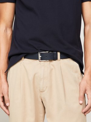 Navy t-shirt paired with beige trousers, featuring a dark blue leather belt. The belt includes a silver rectangular buckle.