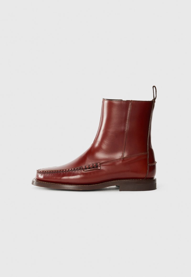 Bottines en cuir rouge foncé, présentant un bout cousu, une finition lisse, et un petit talon carré avec une languette pour un enfilage facile.