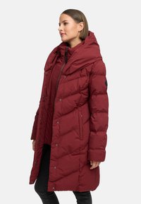 Burgunderfarget pufferjakke med hette, med et diamantquiltet mønster, trykknapper, sidelommer og hel glidelås.