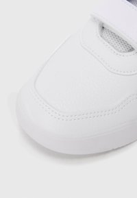 Λευκό αθλητικό παπούτσι με υφασμάτινο συνθετικό επάνω μέρος με υφή, επενδεδυμένο πέλμα και λουράκι με βέλκρο. Στρογγυλεμένη μύτη, διακριτικές λεπτομέρειες ραφής και λαστιχένια σόλα.