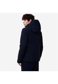 Giacca impermeabile blu navy con cappuccio, caratterizzata da una texture liscia e un design minimalista, vista da dietro. Cuciture di rinforzo visibili.
