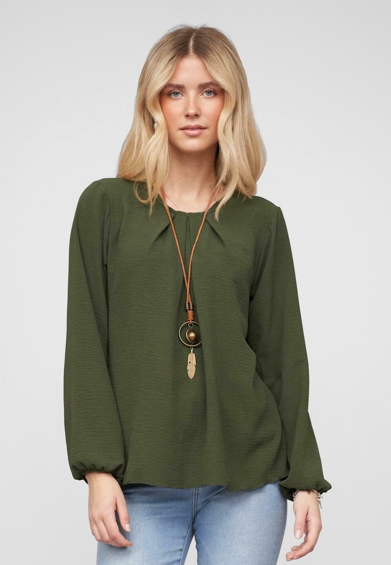 Olijfgroene blouse met lange mouwen, textuurstof en elastische manchetten. Heeft een ronde halslijn en een gelaagd hangertje.
