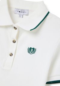 Polo a maniche corte bianco a coste con bordo verde col colletto e sulle maniche, tre bottoni e logo a cuore ricamato verde con la lettera B.