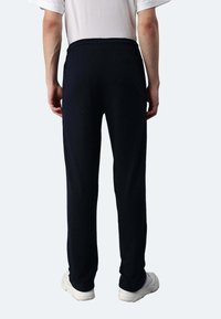 Marineblaue Trainingshosen aus weichem Stoff, mit elastischem Bund und einer Gesäßtasche. Der Schnitt ist locker und gerade.