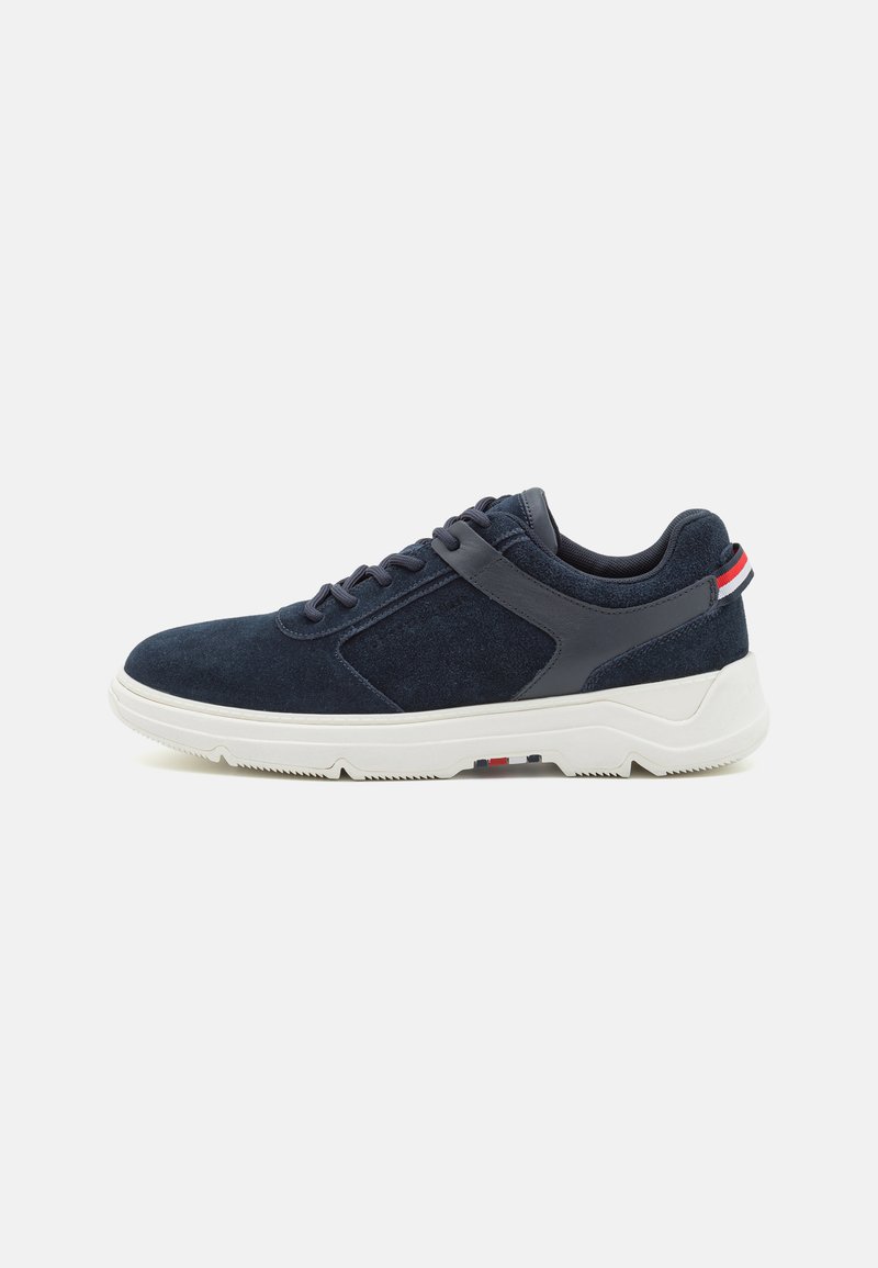 Adidași din suede bleumarin cu un finisaj texturat, talpă din cauciuc albă și dungi de accent roșii și albe pe toc. Design cu șireturi.