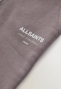 Pelē kokvilnas T-krekls ar baltu uzrakstu "ALL-SAINTS" un papildus japāņu rakstu. Mīksta tekstūra, īsas piedurknes, brīvs piegriezums.