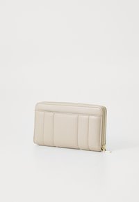 Portafoglio in pelle beige con chiusura a zip, caratterizzato da pannelli verticale cuciti e una chiusura lampo in tono dorato. Texture liscia, forma rettangolare.