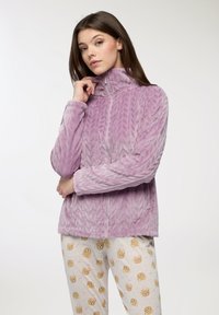 Giacca in pile viola con colletto alto, motivo a zig-zag testurizzato, chiusura con zip e maniche lunghe, abbinata a pantaloni da pigiama chiari con stampe di orsetti.