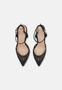 Sapatos de salto alto pretos, com bico fino, design com recortes, tira ajustável no tornozelo e sola interior bege. Exterior de couro liso com um acabamento elegante.