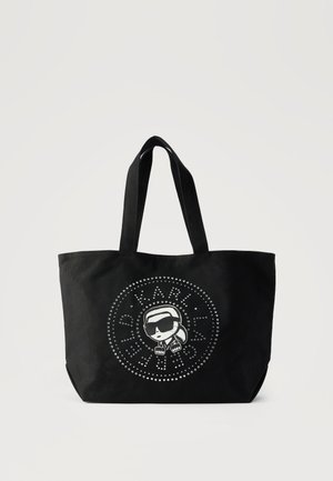 Μαύρη τσάντα χειρός με διπλές λαβές, διακοσμημένη με έναν κυκλικό λογότυπο με καρφιά και μια καρτούν φιγούρα με γυαλιά ηλίου στο κέντρο.
