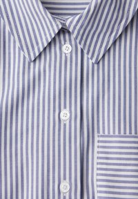 Chemise à rayures verticales bleues et blanches avec des boutons blancs et une poche poitrine à rayures horizontales.