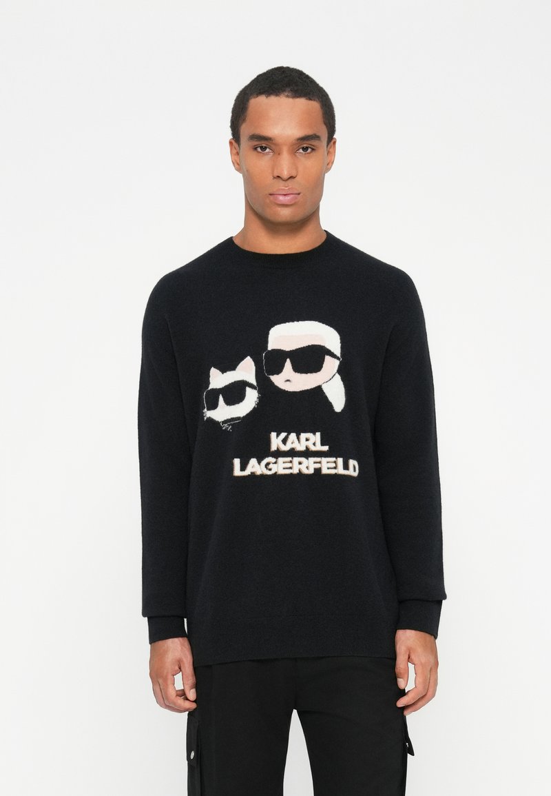 Fekete kötött pulóver, amely két napszemüveget viselő karaktert ábrázoló mintával rendelkezik, alatta a "KARL LAGERFELD" felirattal. Hosszú ujjú, kerek nyakú.