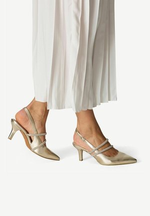 Escarpins slingback dorés métalliques avec bout pointu, accents à double bride et talon kitten de 2,5 pouces. Texture lisse et finition polie.