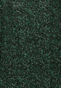 Tela negra con un patrón floral verde, que presenta intrincados diseños de enredaderas y pequeñas flores, creando una apariencia texturizada y en capas.