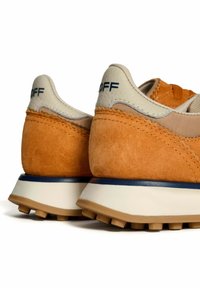 Sneaker in suede arancione con accenti beige, dotate di un tallone testurizzato, suola intermedia bianca e suola in gomma con piccoli tasselli.