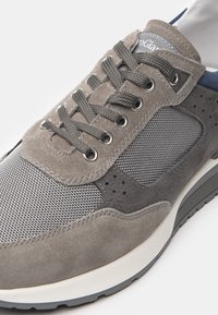 Sneaker grigio realizzata in materiali scamosciati e mesh, con lacci rotondi, occhielli in metallo e una suola in gomma testurizzata. Accenti di colore grigio e navy degni di nota.