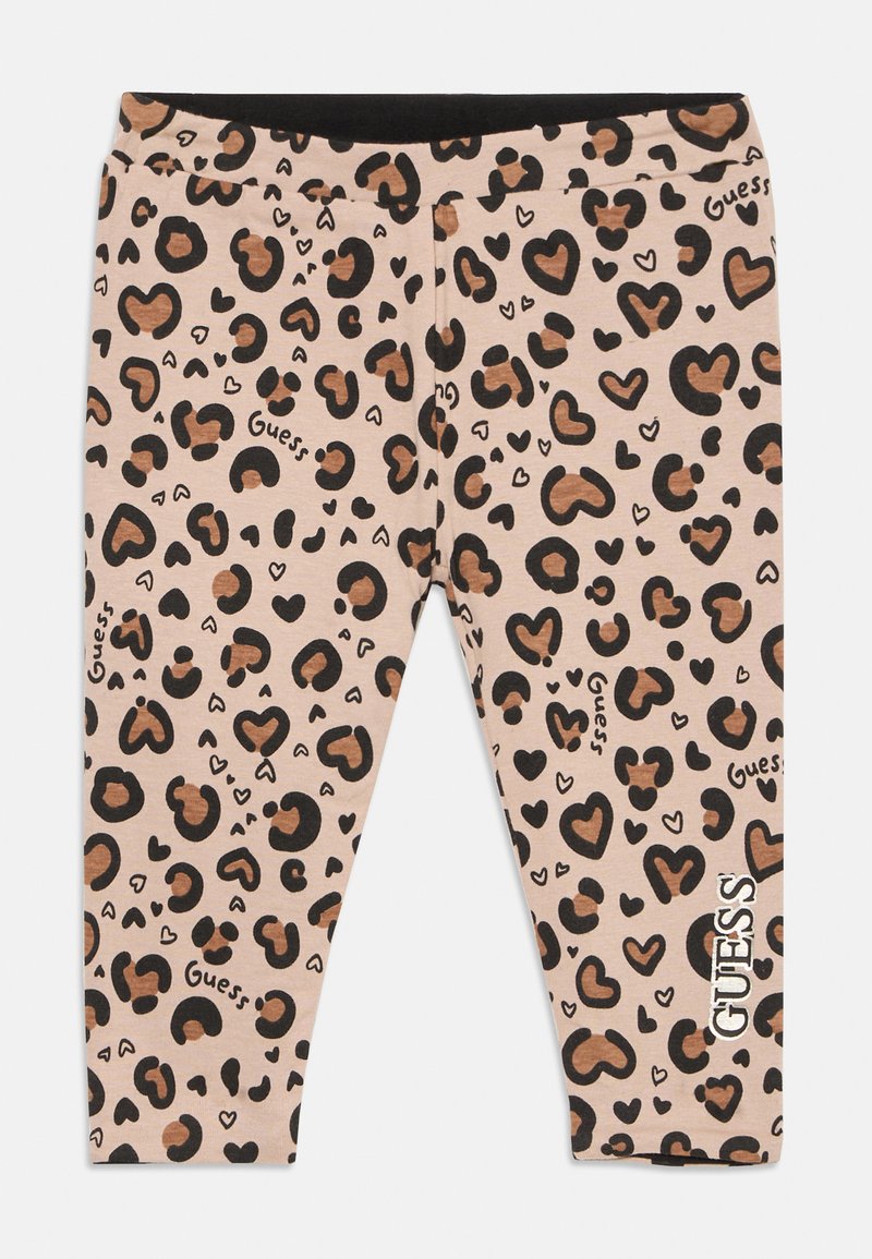 Beige legice s črnim in rjavim vzorcem srčkov in leoparda, besedilo logotipa "Guess" po celotnem oblačilu in vertikalno na spodnjem delu noge.