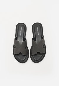 Sorte svarte sandaler med åpen tå og bred stroppdesign laget av mykt stoff. Teksturert svart såle for bedre grep.
