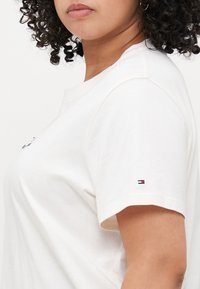 Witte katoenen t-shirt met een ronde hals, korte mouwen en een klein geborduurd logo accent op de linkermouw.