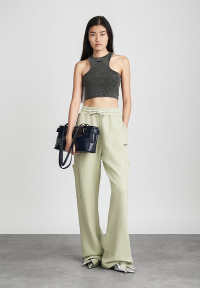 Bezrukávový tmavozelený rebrovaný crop top, voľné svetlozelené cargo nohavice a malá námornícka kabelka. Strieborné špicaté topánky s detailom na zips.