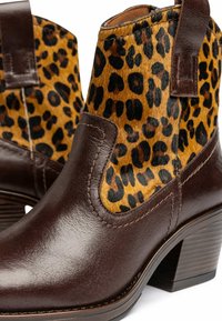 Bottines en cuir marron avec un dessus en textile imprimé léopard, dotées d'un talon empilé et d'une languette latérale pour un enfilage facile.