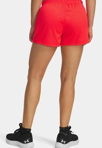 Rode gaas sportshorts met een elastische tailleband, voorzien van een loose fit en zijnaad. Gepaarde met zwarte sneakers en enkelsokken.